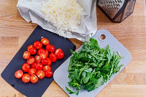 Gehobelter Parmesan, halbierte Kirschtomaten und klein geschnittener Rucola f&uuml;r Spaghettisalat