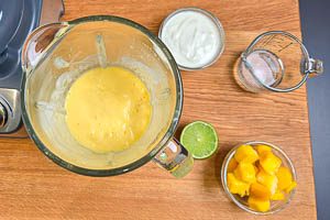 Mango, Joghurt, Wasser und Limettensaft für den Mango Lassi gemeinsam pürieren