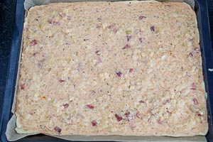 Die Zwiebelkuchen-Masse auf das Backblech verteilen