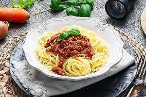 Bolognese-So&szlig;e mit Spaghetti auf einem Teller angerichtet servieren