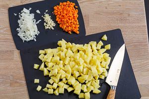 Kartoffeln, Möhre, Zwiebel und Knoblauch würfeln