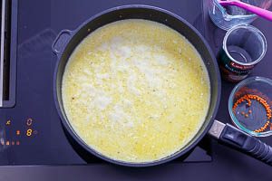 Gemüsebrühe, Kokosmilch, rote Linsen und gelbe Currypaste in die Pfanne geben