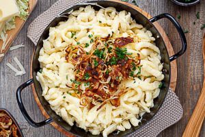 K&auml;sesp&auml;tzle mit R&ouml;stzwiebeln und Schnittlauch garnieren