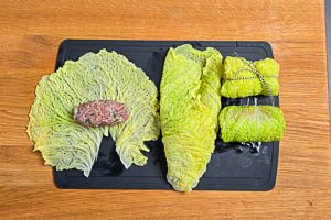 Hackfleisch in die Mitte geben, die Kohlroulade aufrollen und mit K&uuml;chengarn zu einem P&auml;ckchen schn&uuml;ren.