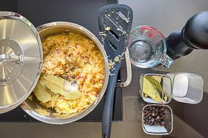 Sauerkraut zu den w&uuml;rzigen Zutaten in den Topf geben