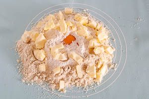 Eine Prise Salz und Butterst&uuml;cke &uuml;ber dem Mehl verteilen