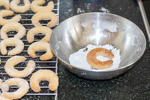 Frisch gebackene Vanillekipferl-Pl&auml;tzchen in Vanillezucker w&auml;lzen