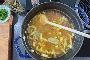 Mit Brühe ablöschen und Lorbeerblätter hinzugeben.
