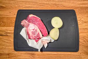 Suppenfleisch abwaschen und Zwiebel einmal durchschneiden.