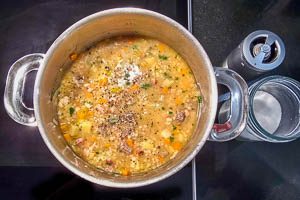 Petersilie und Suppenfleisch zur Suppe geben.