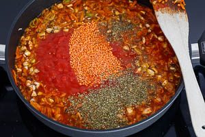 Rote Linsen und Gemüsebrühe zum Gemüse in die Pfanne