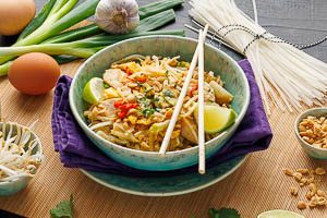 Pad Thai mit Koriander, gehackten Erdnüssen und Limette garnieren und in einer Schale servieren