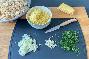 Weizenbr&ouml;tchen vorbereiten, Zwiebel, Knoblauchzehe und Petersilie klein schnippeln und Bergk&auml;se grob reiben.
