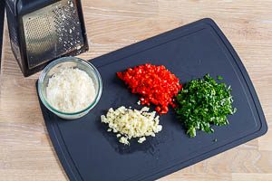 Petersilie, Peperoni und Knoblauchzehen schneiden und Parmesan reiben