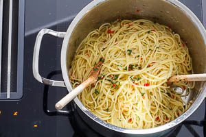 Aglio e olio zu den Spaghetti geben und vermengen