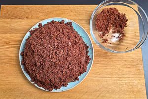 Kr&uuml;mel aus dem Kuchenteig auf der Sahnekuppel verteilen