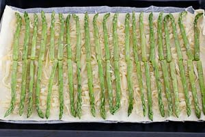 Gr&uuml;nspargel auf dem Bl&auml;tterteig mit K&auml;se verteilen