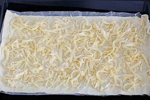 K&auml;se auf dem Bl&auml;tterteig verteilen