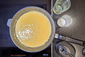 Sahne und Hühnerbrühe zu den Zwiebeln und dem Knoblauch geben. Hitze runter drehen und den Parmesan hinzugeben.