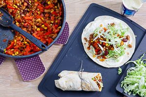 Erw&auml;rme die Tortillas und verteile deine F&uuml;llung aus Gem&uuml;se und Fleisch mit etwas Cr&egrave;me Fra&icirc;che darauf.
