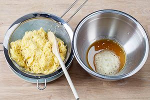 Fl&uuml;ssigkeit durch ein Sieb aus den geriebenen Kartoffeln dr&uuml;cken