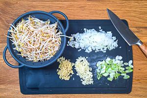 Zwiebeln, Knoblauch, Ingwer, Fr&uuml;hlingszwiebeln und Sojasprossen vorbereiten