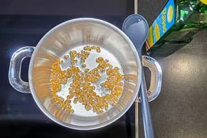 &Ouml;l erhitzen und Popcorn-Mais zugeben.
