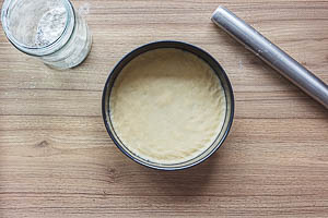 Boden f&uuml;r den gedeckten Apfelkuchen ausrollen und in die Form dr&uuml;cken.
