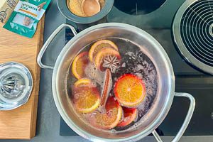 Wein, Orangenscheiben und Gew&uuml;rze im Topf erhitzen
