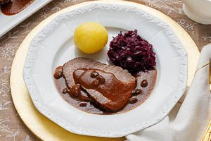 Sauerbraten warm mit Bratenso&szlig;e, Kartoffelkn&ouml;deln und Rotkohl servieren