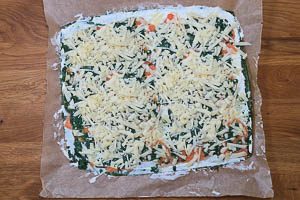 Geriebenen Bergk&auml;se auf dem Spinat verstreuen