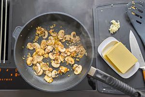Butter, Zwiebeln und Champignons in einer Pfanne anr&ouml;sten