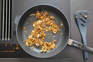 Eingeweichte Pilze und Knoblauchw&uuml;rfel in die Pfanne geben