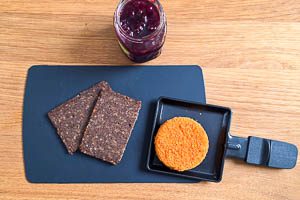 Backcamembert ins Pf&auml;nnchen geben und danach mit Preiselbeermarmelade und Schwarzbrot garnieren.
