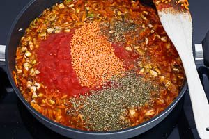 Gemüse mit Brühe und stückigen Tomaten ablöschen und rote Linsen hinzugeben