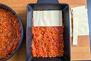 Lasagneplatten und Rote-Linsen-Soße abwechselnd in die Auflaufform schichten