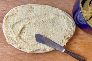 Für Polenta-Schnitten die warme Polenta auf ein Holzbrett streichen