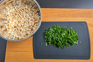 Bärlauch in Streifen und trockene Brötchen in Würfel schneiden