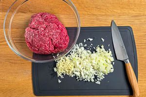 Zwiebeln klein hacken und Hackfleisch in die Schüssel geben.