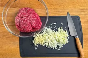 Zwiebeln klein hacken und Hackfleisch in die Schüssel geben.