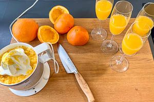 Orangen auspressen und Saft auf die Gläser verteilen.