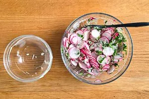 Dressing mit Radieschen und Petersilie vermengen
