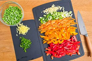 Knoblauch, Ingwer, Peperoni und Gem&uuml;se kleinschneiden