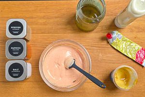 Basis aus Mayo, Gurkenwasser, Senf, Tomatenmark, Paprikapulver, Salt und schwarzem Pfeffer anrühren.