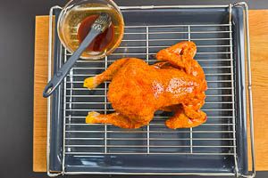 Hähnchen auf ein Rost und darunter ein Backblech, mit Marinade bestreichen
