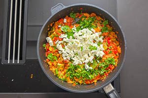 Menemen mit Petersilie und Fetawürfeln bestreuen