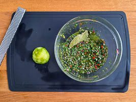Limettenzeste, Limettensaft, Zwiebel und Peperoniwürfel unterrühren, Lorbeerblatt dazugeben und zwei Stunden ziehen lassen