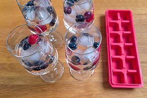 Beeren, Eiswürfel und Minze ins Glas geben