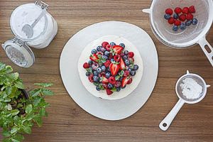 Nach dem Kühlen mit Puderzucker bestäuben und die restlichen Beeren auf dem Kuchen verteilen