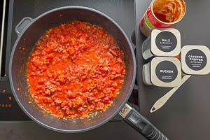 Stückige Tomaten dazugeben und dann mit Salz, Cayennepfeffer und Zucker abschmecken